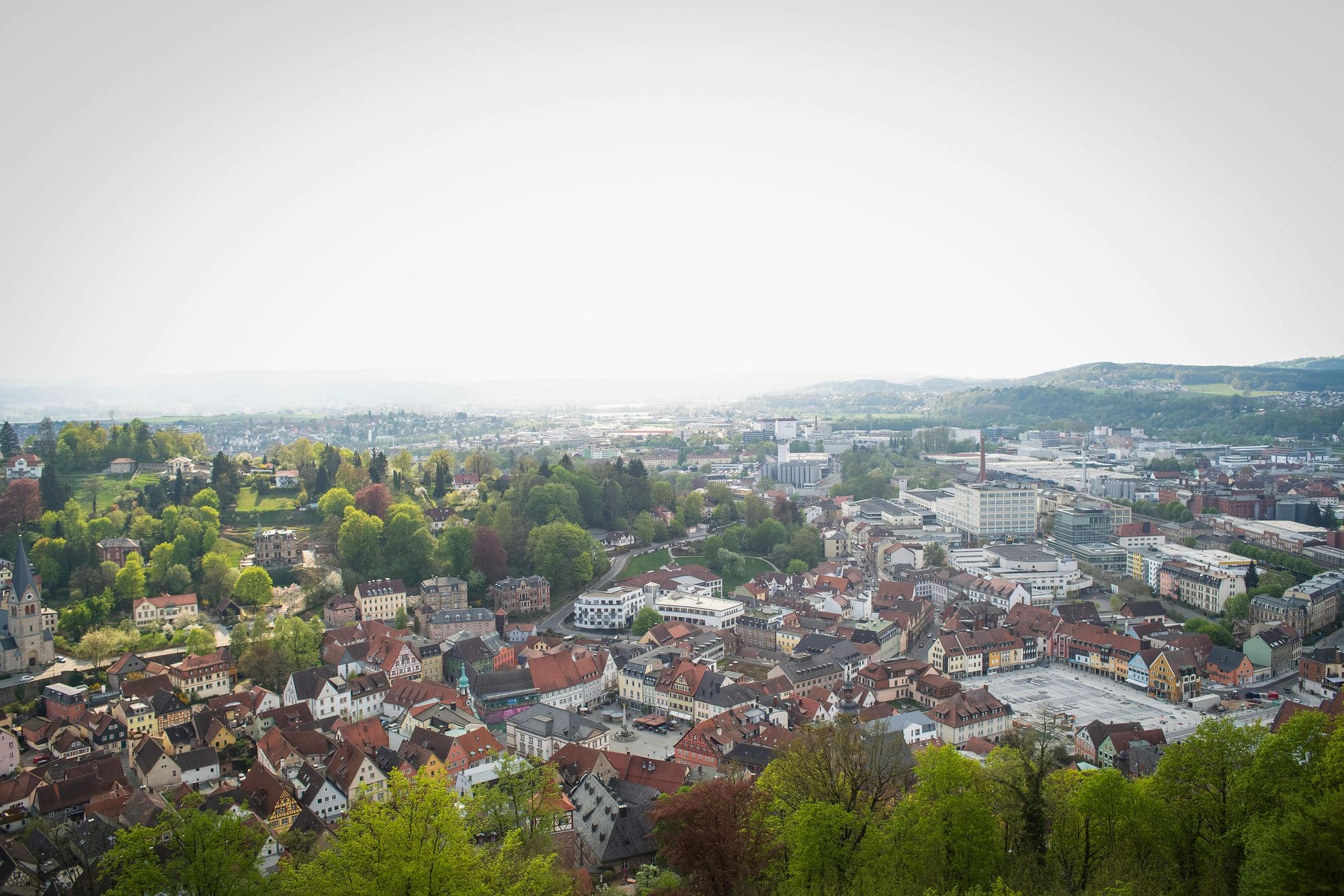Aerial view over a European town with red roofs and green hills