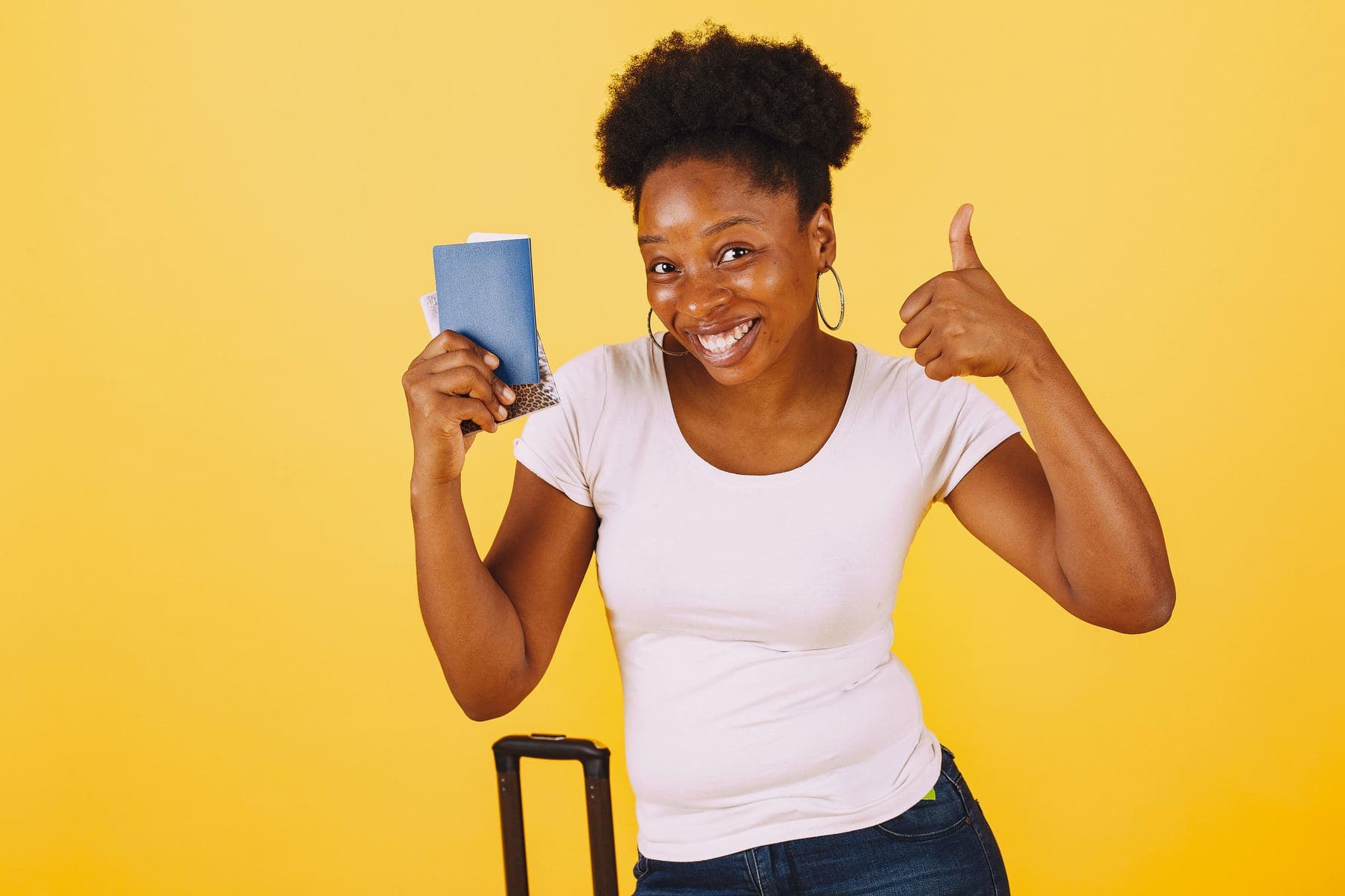 Smiling traveller holding a passport and giving a thumbs up